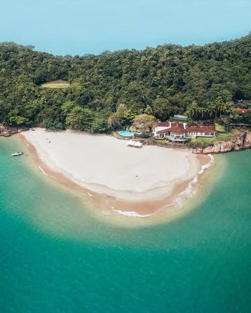 Praia em forma de ponta da Ilha dos Porcos, com casa e piscina entre a mata