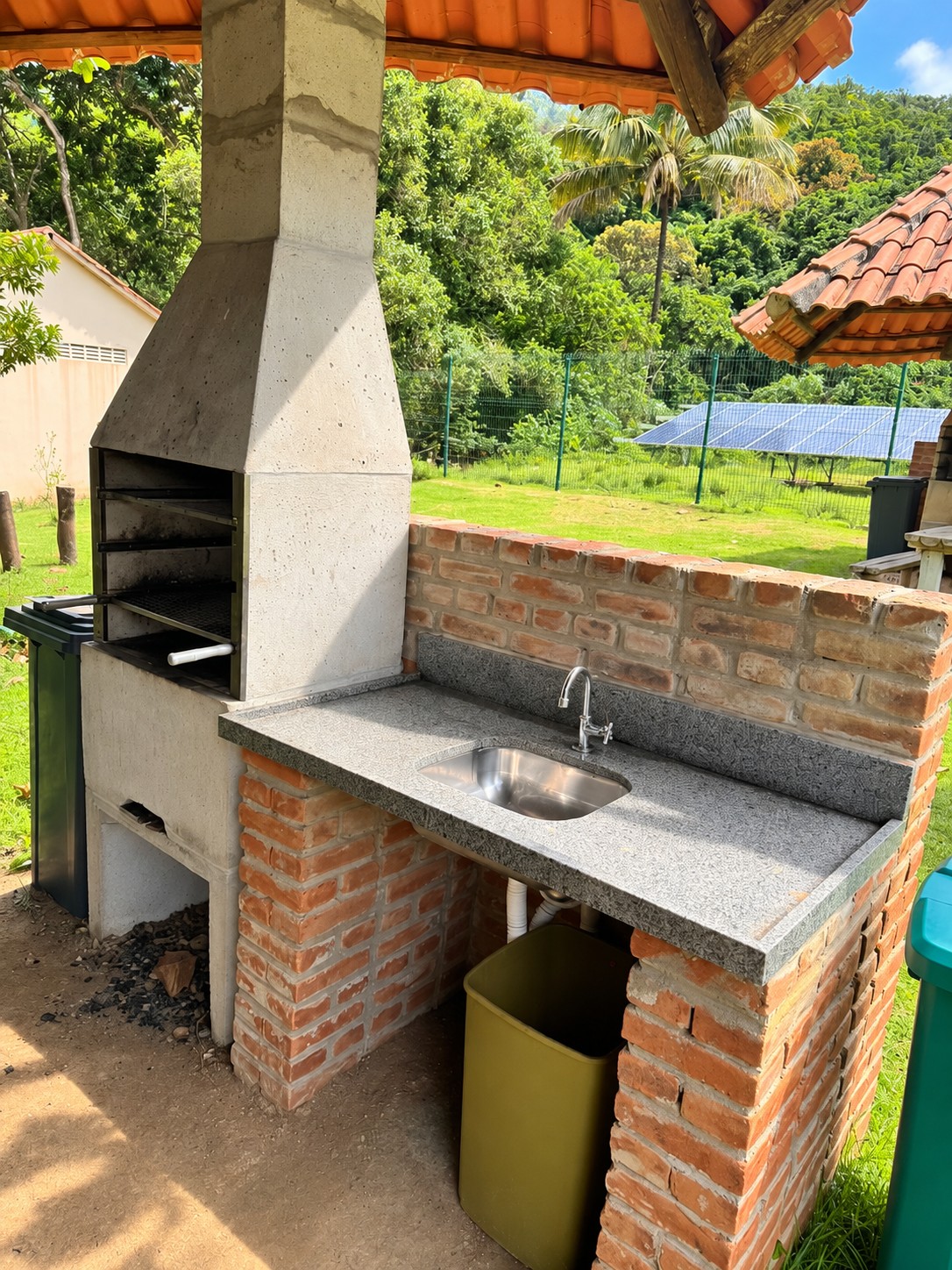 Churrasqueira com bancada de granito, pia e lixeiras